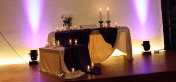 Altarraum mit Kerzen und zwei lila Scheinwerfern