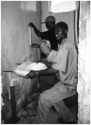 Zwei afrikanische Helfer und Gerd Kunstmann montieren ein Waschbecken