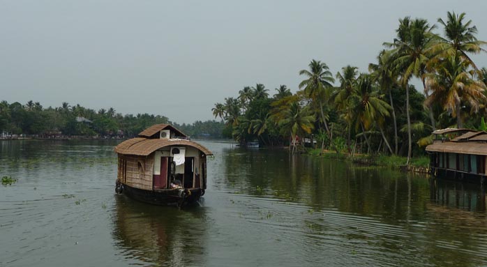 Indisches Hausboot auf breitem Fluss mit grünen Ufern