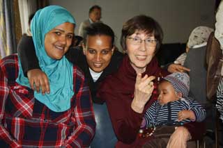 Ältere Dame von der Flüchtlingshilfe mit zwei jungen Flüchtlingsfrauen und kleinem Kind