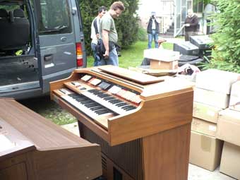 Vor dem Kleinbus steht die ausgeladene Ware: 2 Elektro-Orgeln, Computer, Kisten