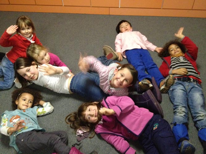 Acht Kinder des Kindertreffs unserer Gemeinde liegen am Boden und lachen in die Kamera